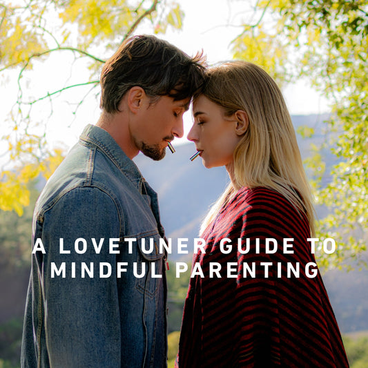 Man and woman standing forehead to forehead, each using a Lovetuner, surrounded by nature, illustrating mindful parenting and emotional connection.