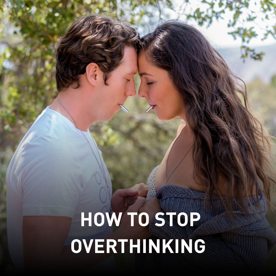 Man and woman standing close with foreheads touching, both holding metal straws in their mouths, surrounded by nature. Text overlay: 'How to Stop Overthinking