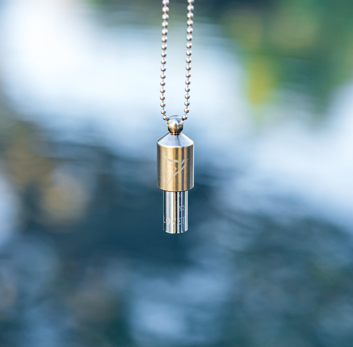 Close up picture of the silver Lovetuner on the ball chain with a gradient blue background.