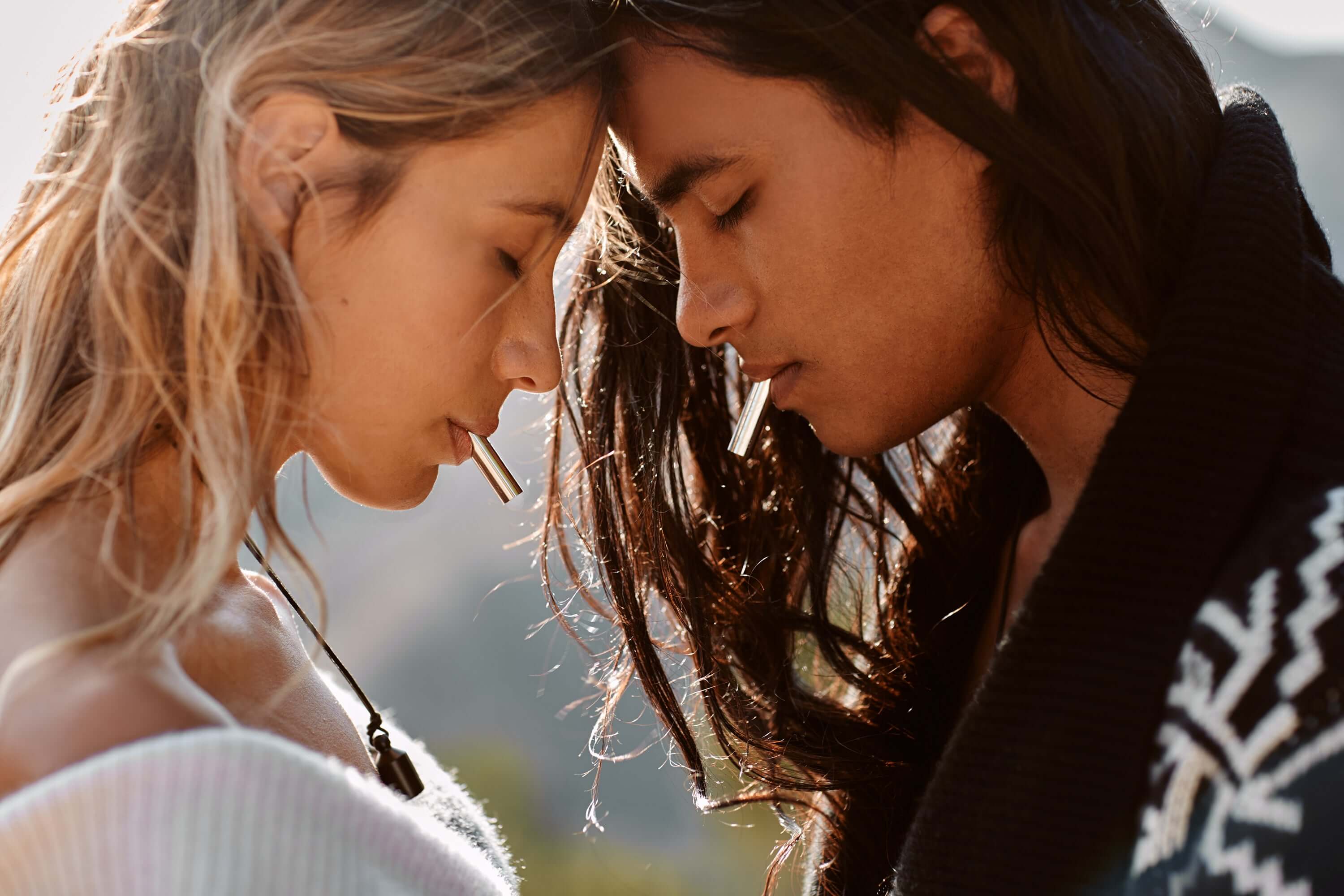 Man & woman meditate, eyes closed, using LoveTuner device. Harmony in their breath, serene atmosphere