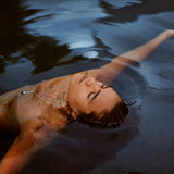 Person floating in water breathing through the Lovetuner 528Hz breathing device