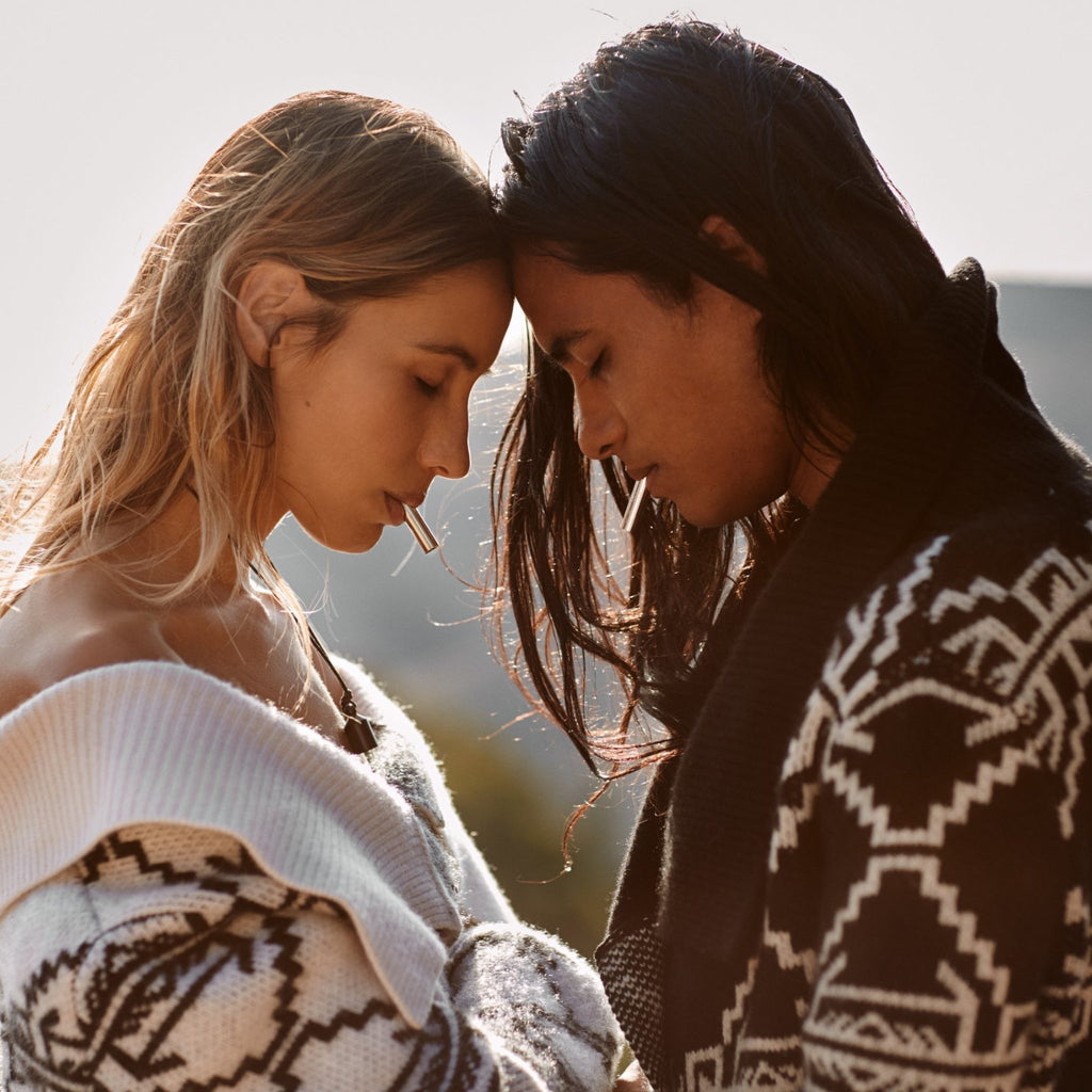 Couple breathing together with Lovetuner 528Hz breathing necklaces, foreheads touching outdoors