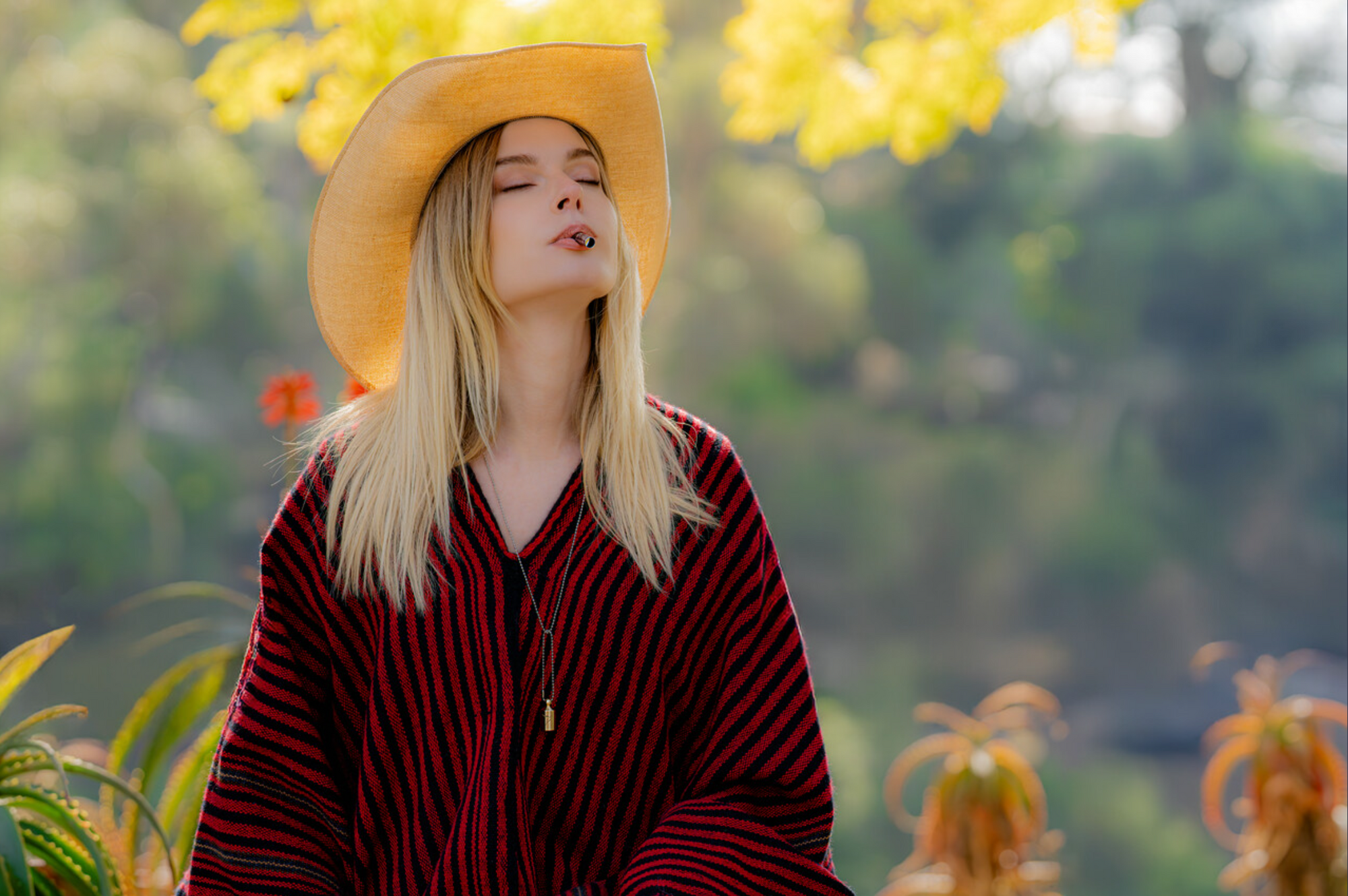Woman wearing a wide brim hat and red patterned shirt in a garden setting using the Lovetuner