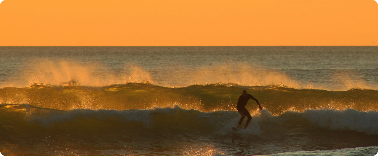A man riding a wave at sunset