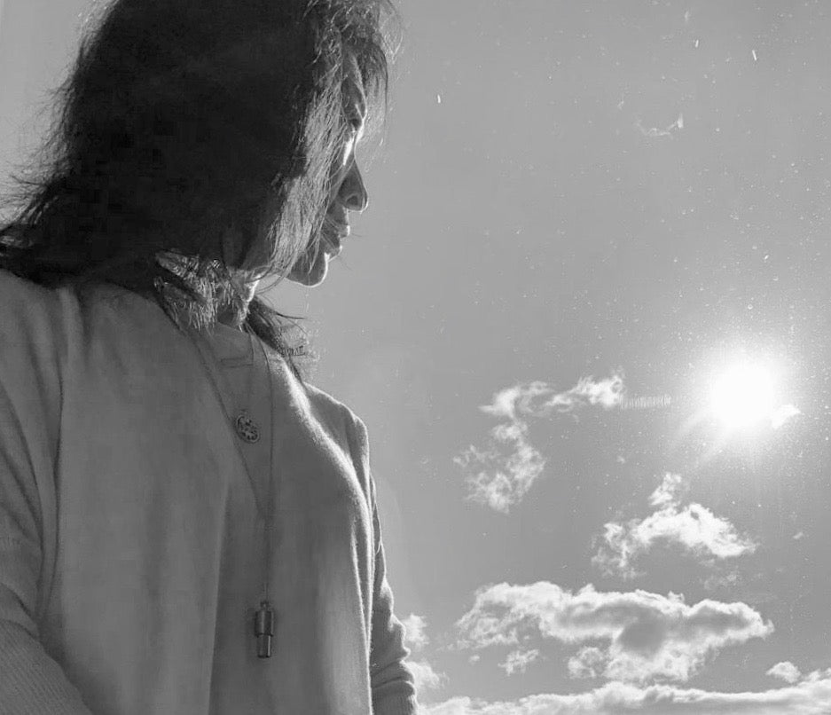 A black and white photo looking up at a person wearing a Lovetuner against a clear and sunny sky