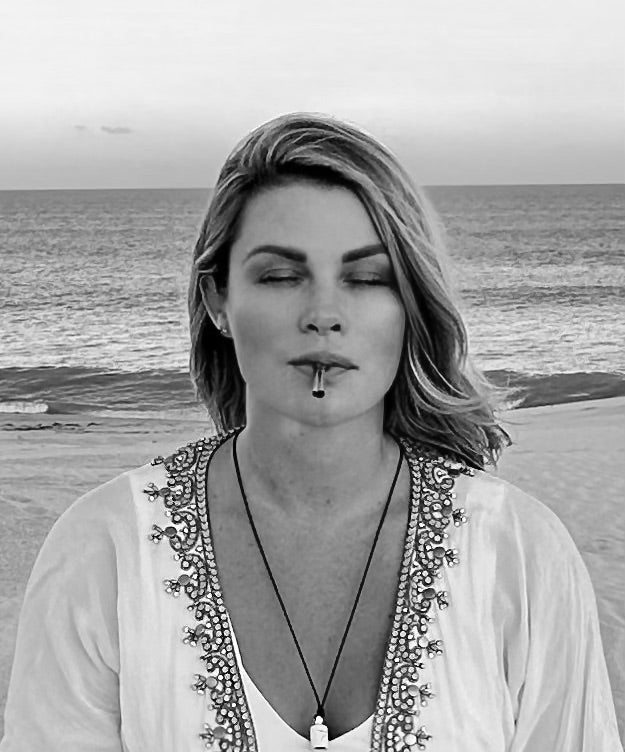 A black and white photo of a woman in a white outfit using the Lovetuner on the beach with her eyes closed