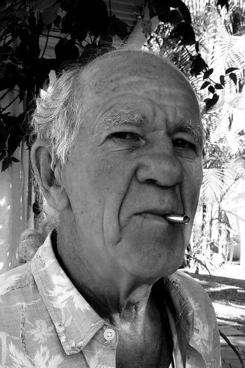 A black and white photo of a bald old man wearing a palm-tree printed shirt using a Lovetuner