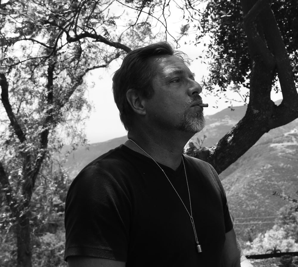 A black and white photo of a man using the Lovetuner beneath the shade of trees