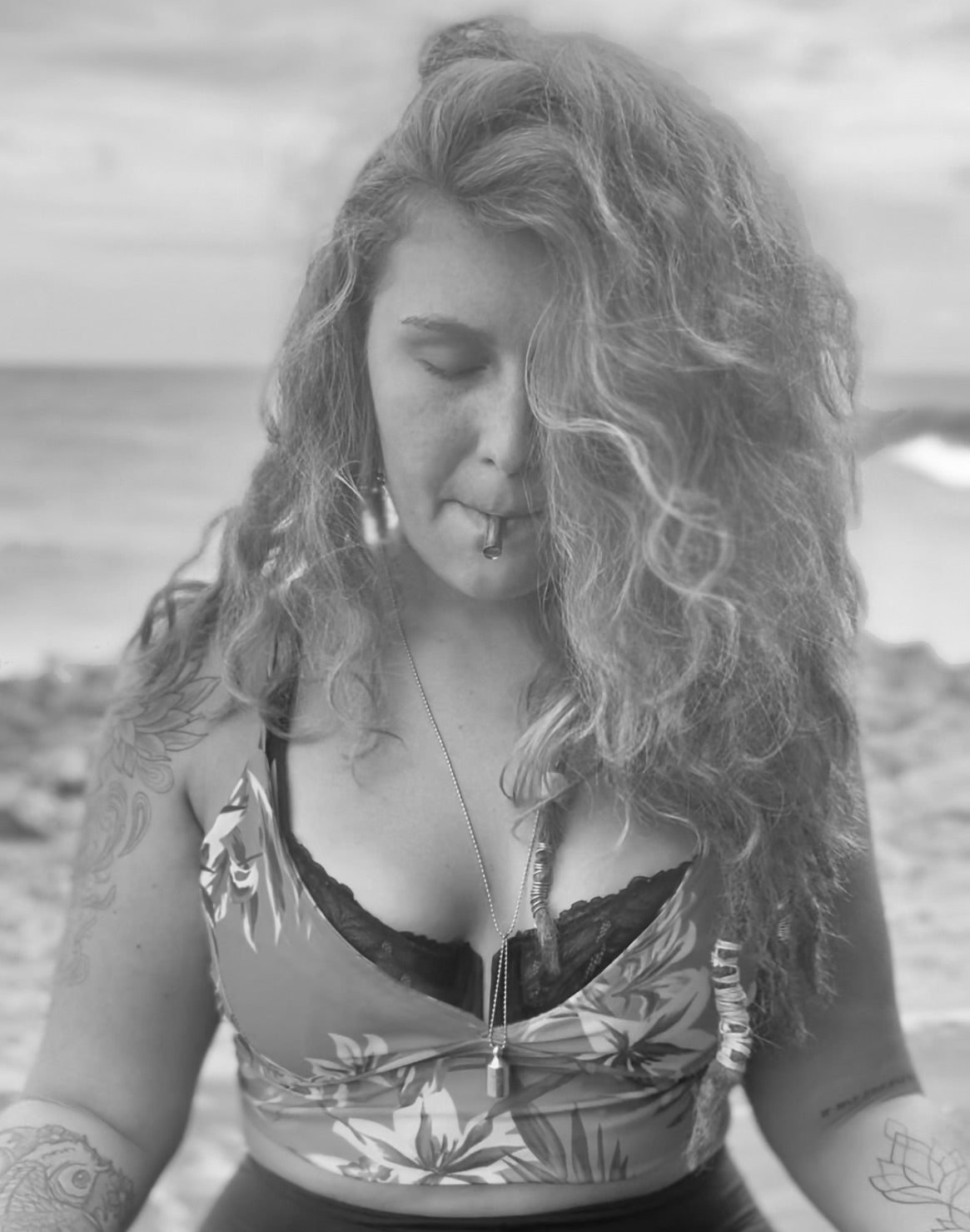 A black and white photo of a woman with closed eyes using the Lovetuner on a rocky beach
