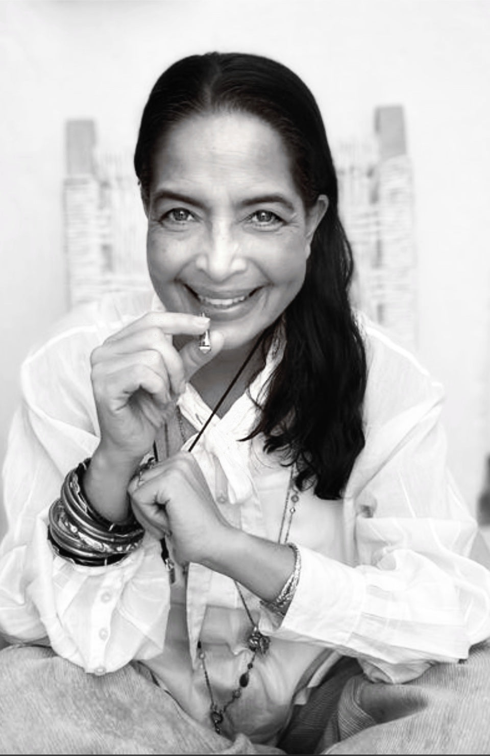 A black and white photo of a woman in a linen shirt with many bracelets on her wrist using the Lovetuner